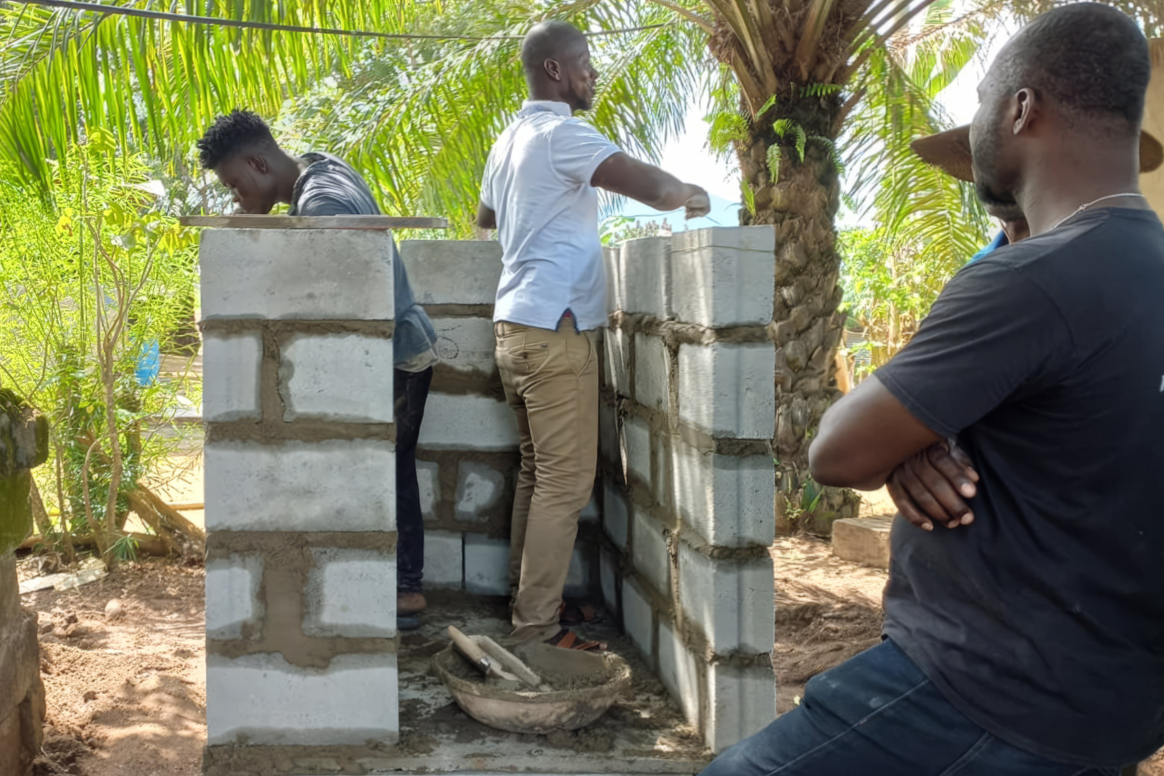 Workers in Ghana building with bricks made from sludge
