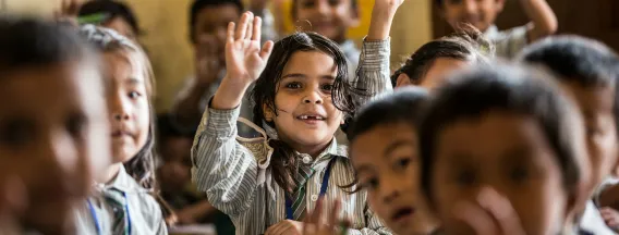 Children in a classroom raising their hands