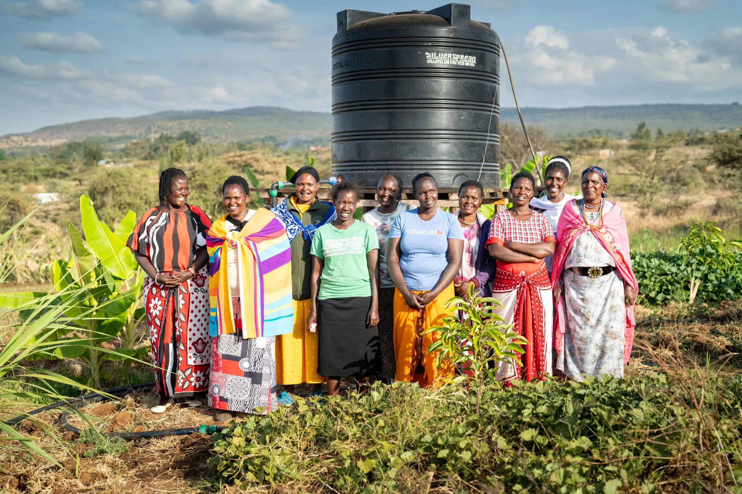 Group of women farmers in Kenya proudly showing their water tank
